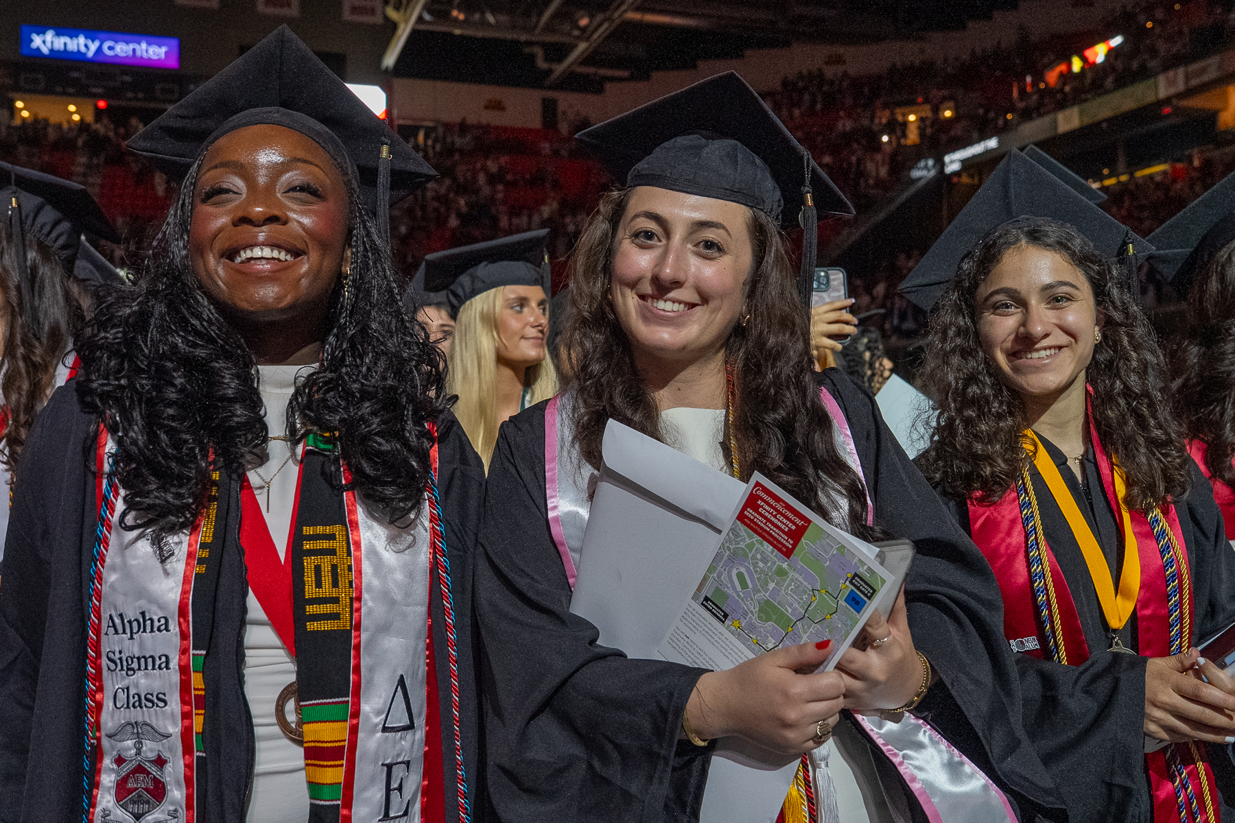 Three graduates on the arena floor at the Xfinity Center