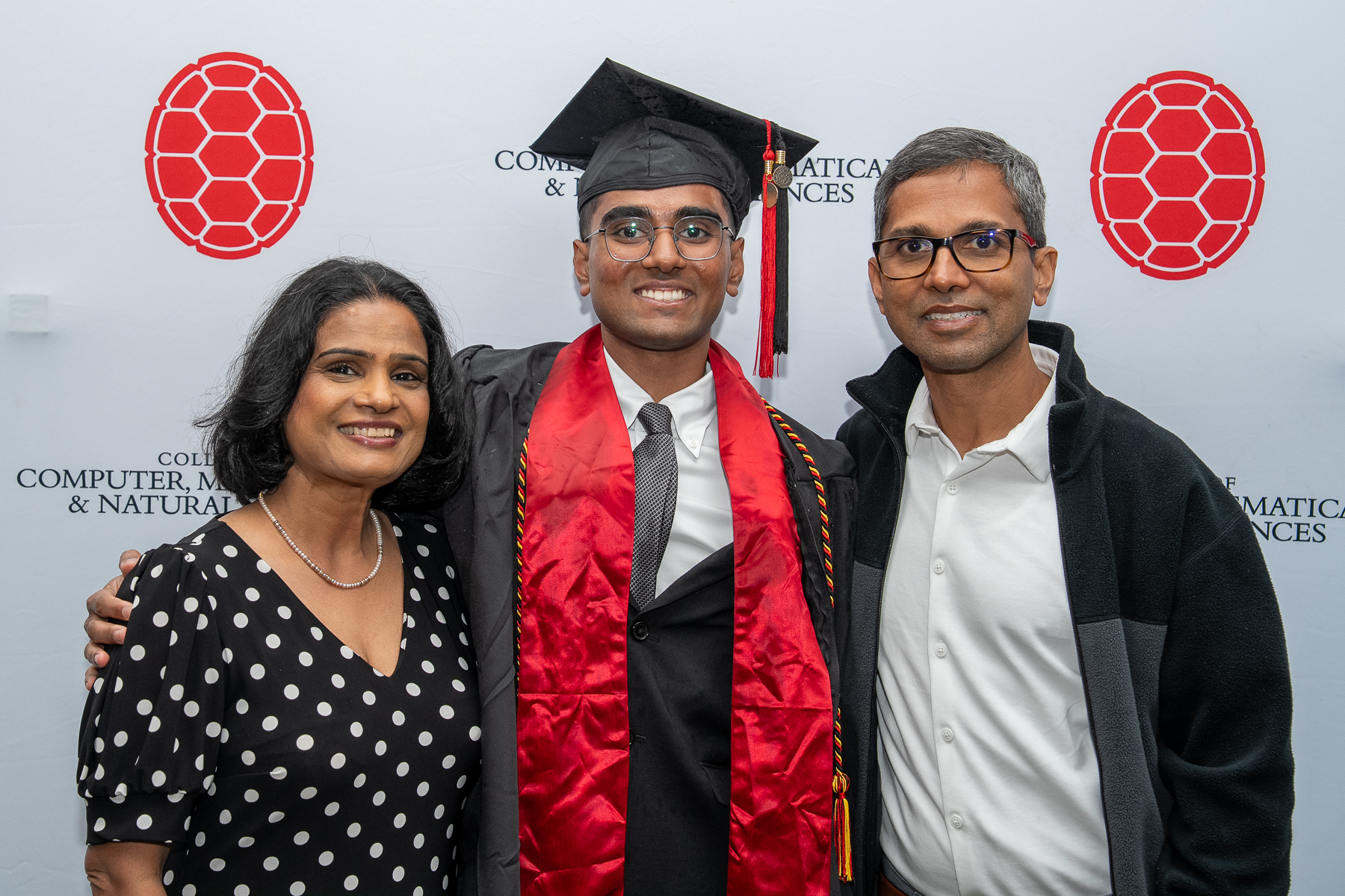 Graduate stands between two family members