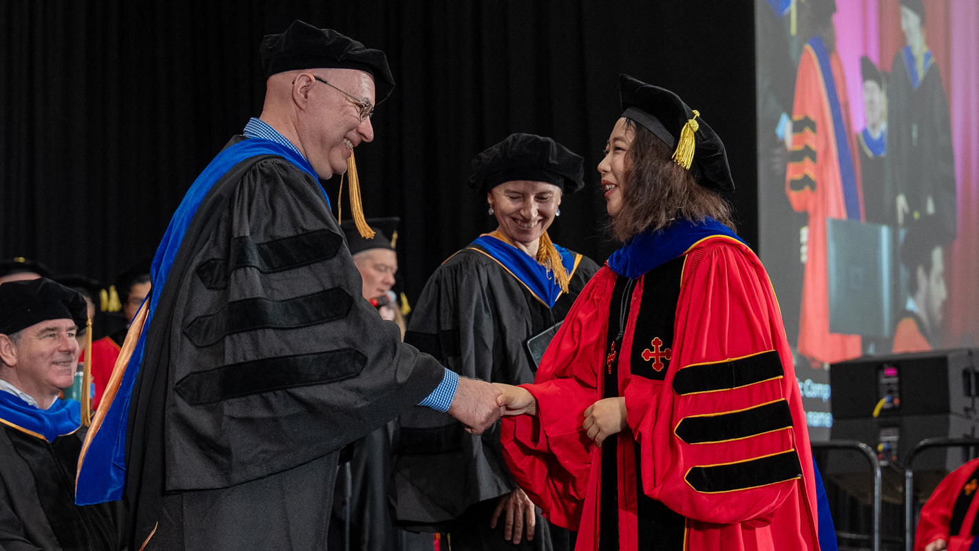 A newly-minted Ph.D. recipient shaking hands with her advisor.