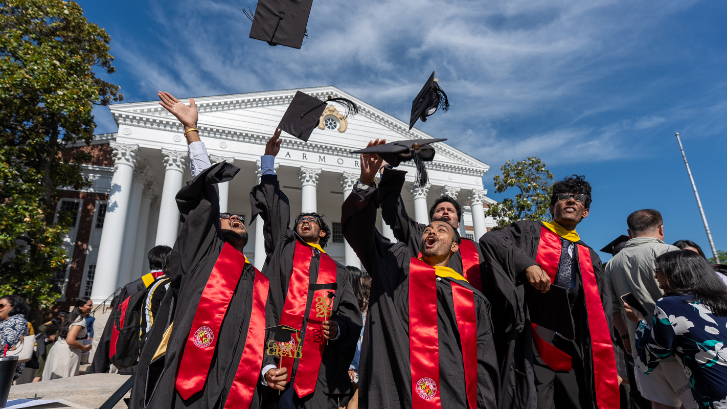 A group of master's degree students tossing their caps in the air.