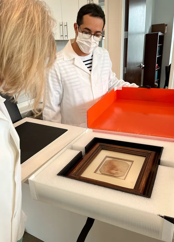 researcher wearing white mask unpacks “Holy Child” sketch