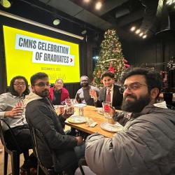 A group of 6 CMNS students at a party, lifting glasses with the SCIENCE TERP logo on them.