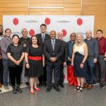 Group of employee awardees standing and smiling in front of a CMNS branded backdrop